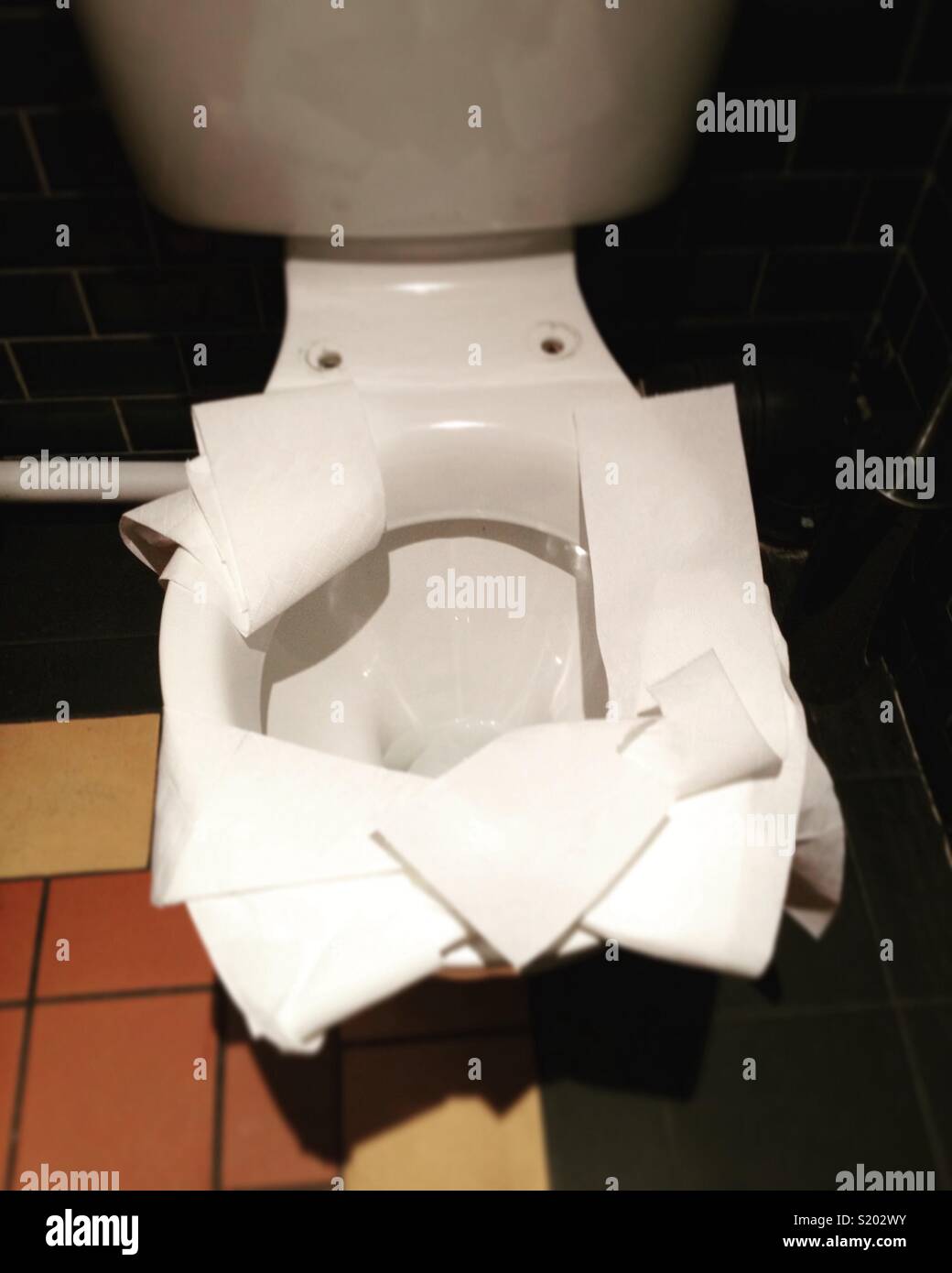 Toilet without a seat but with a paper covering all around the rim, apparently placed by someone who is worried about hygiene, dirt & germs. Stock Photo