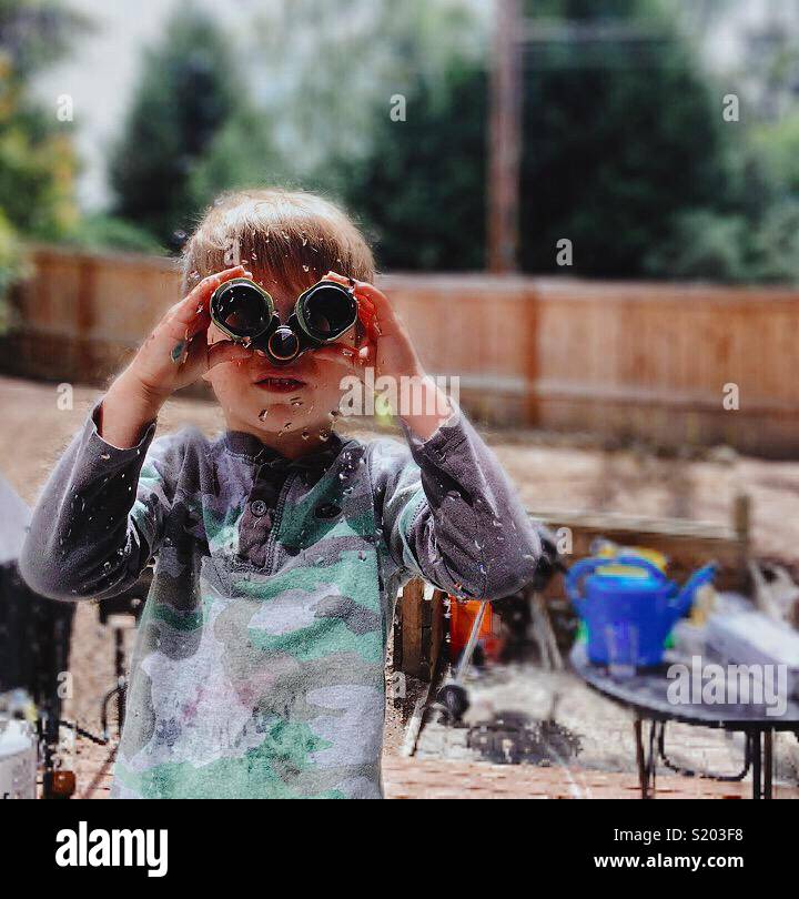 Boy looking through binoculars at window Stock Photo Alamy