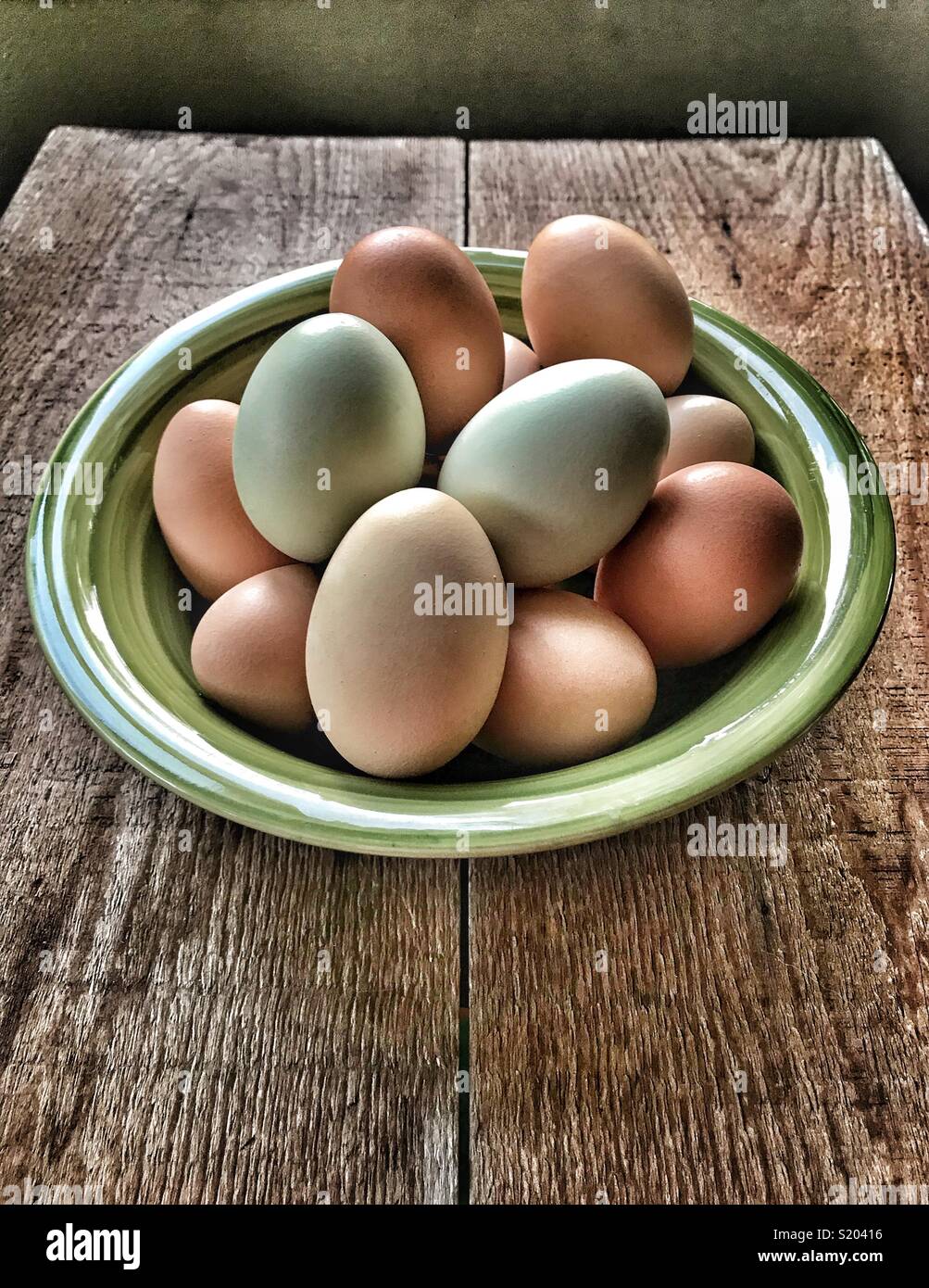 Freshly collected backyard chicken eggs in green bowl on wood table - Smartphone Captured Stock Image