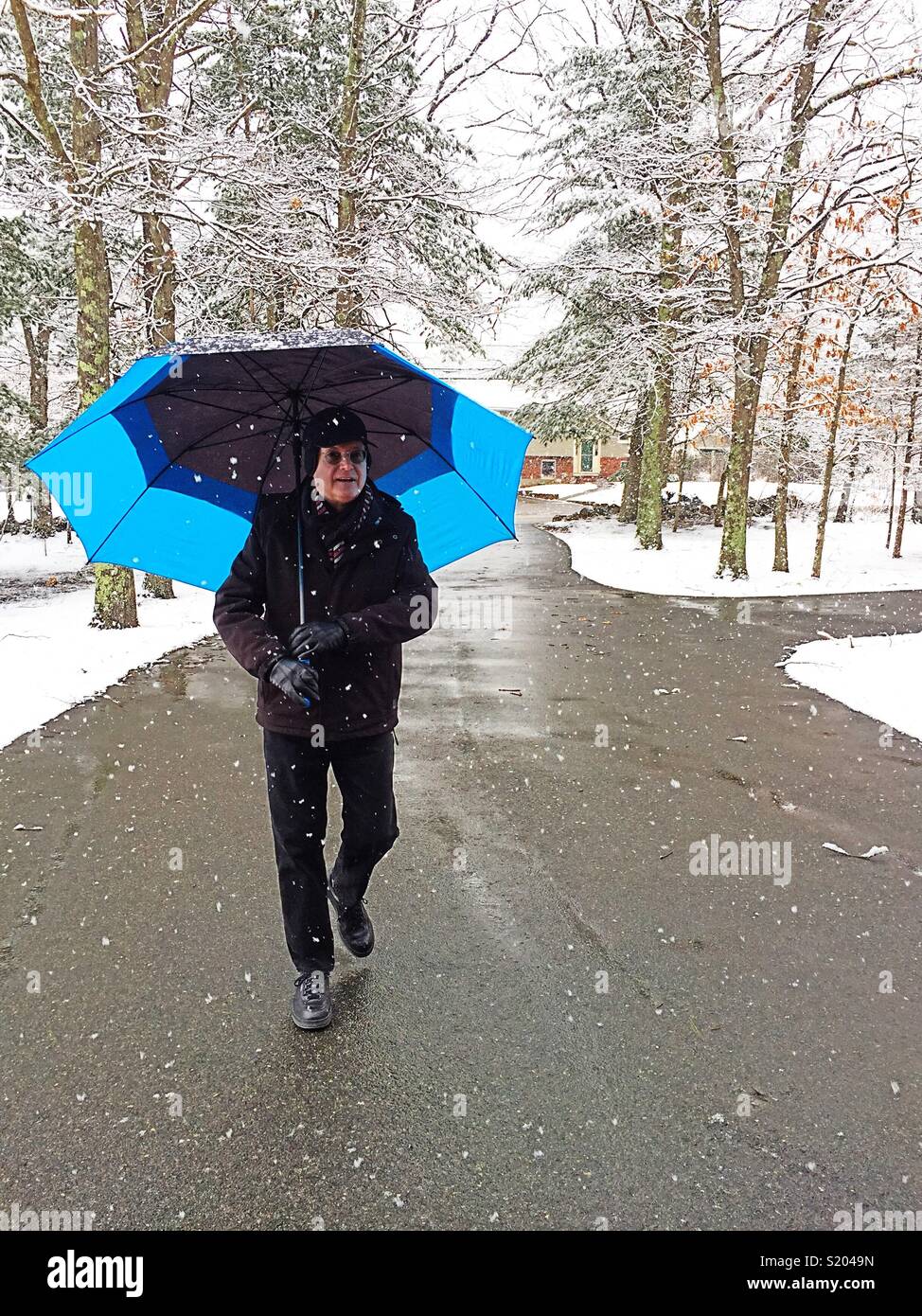 Mature man with an umbrella walking in a new England snowstorm, USA - Smartphone Captured Stock Image