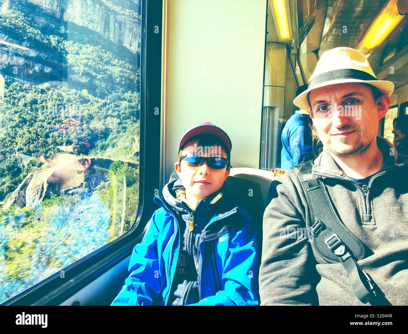 Father and son travel together on a train while on holiday. - Smartphone Captured Stock Image
