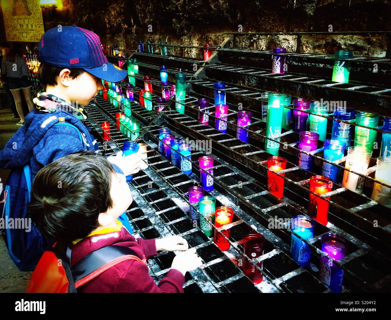 Young brothers light a candle and say a prayer at Montserrat in Spain. Stock Photo