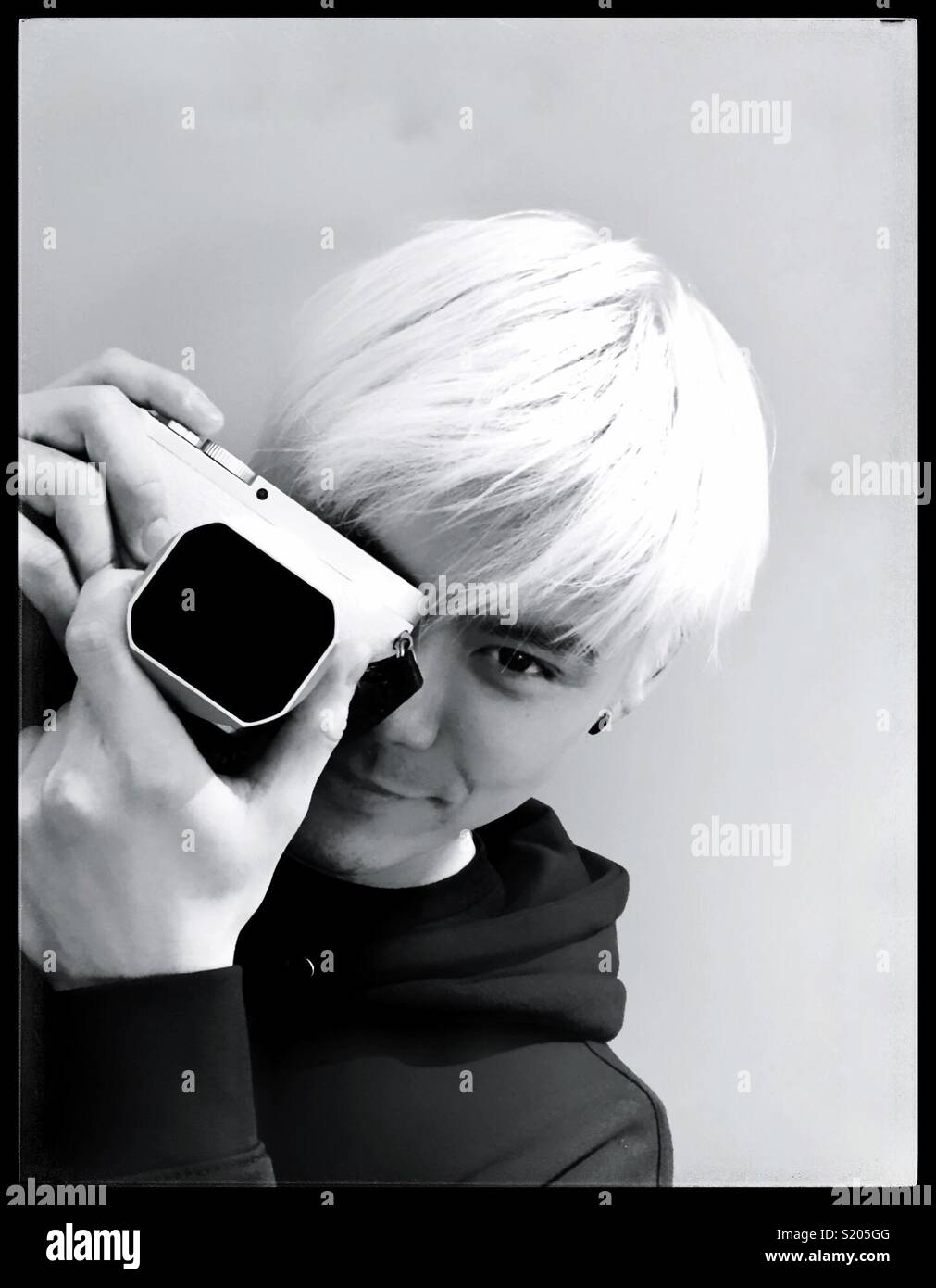 Young oriental man with white hair holding a camera. - Smartphone Captured Stock Image