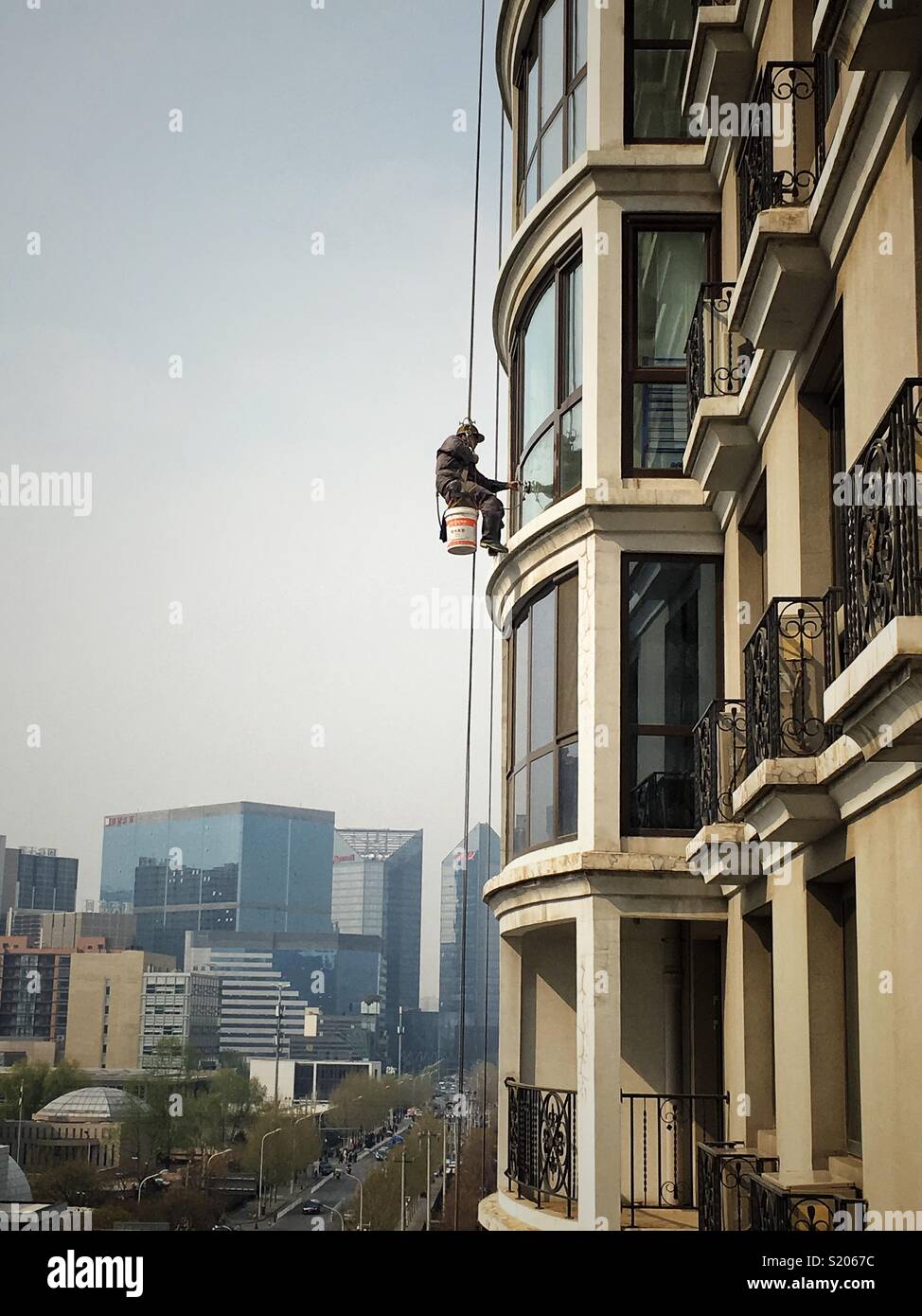 Climber worker doing cleaning job of a  hotel in Beijing, China - Smartphone Captured Stock Image