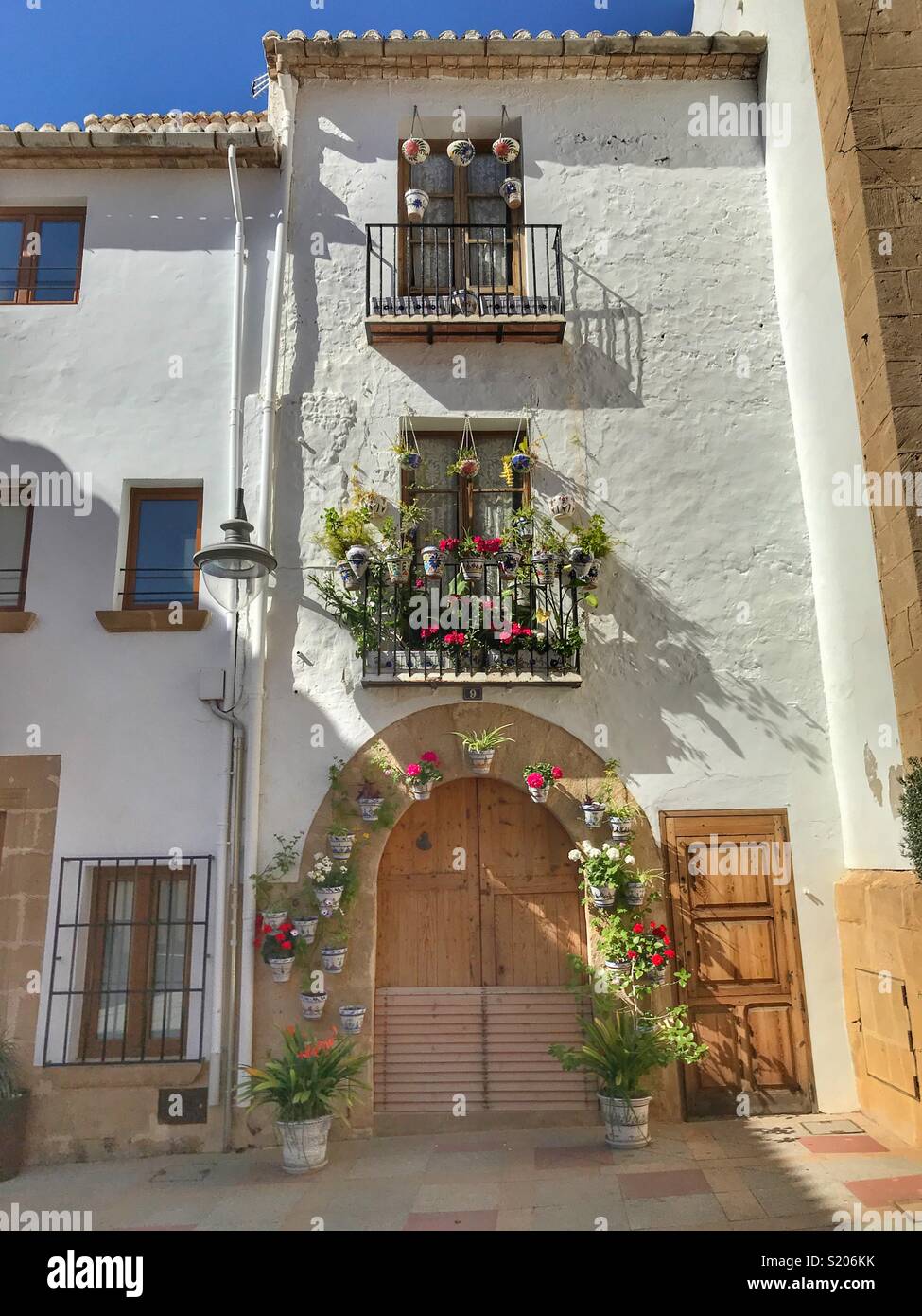 A town house decorated with flowering pot plants around the door and on the balcony in the Old Town area of Javea/ Xabia, Alicante, Spain - Smartphone Captured Stock Image