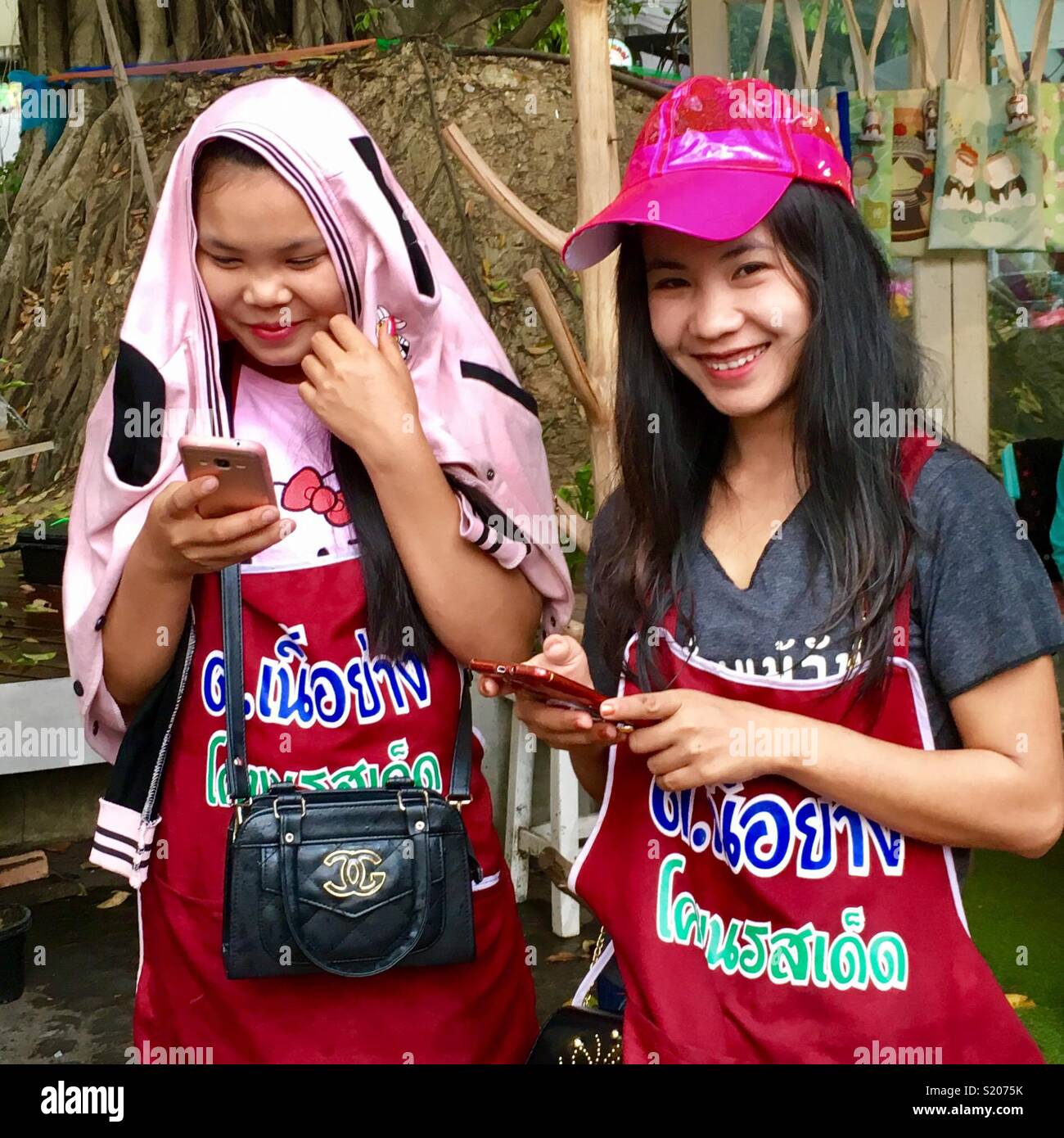 Young Thai salesladies on their mobile phone, Chiang Mai, Thailand - Smartphone Captured Stock Image