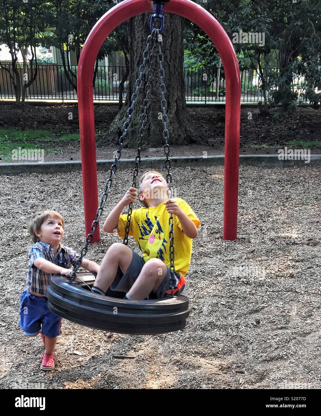 Boys on tire swing at playground Stock Photo Alamy