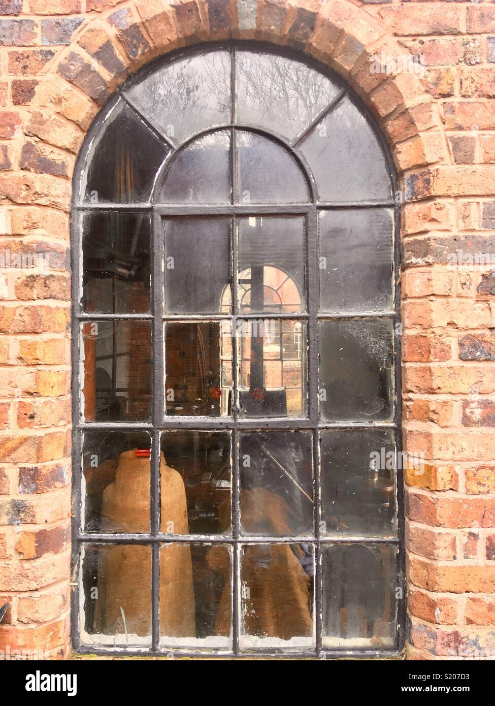 Old arched steel window, Crittal style, in an industrial workshop - Smartphone Captured Stock Image