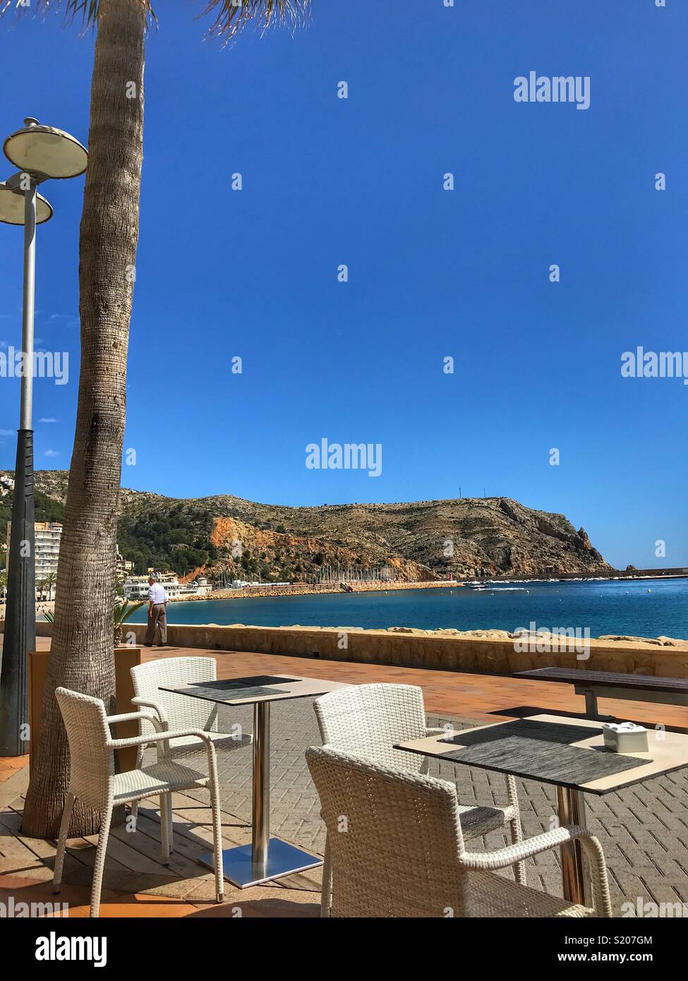 Restaurant / cafe tables on the waterfront promenade in the port area of Javea / Xabia on the Costa Blanca, Alicante Province, Comunidad Valenciana, Spain - Smartphone Captured Stock Image