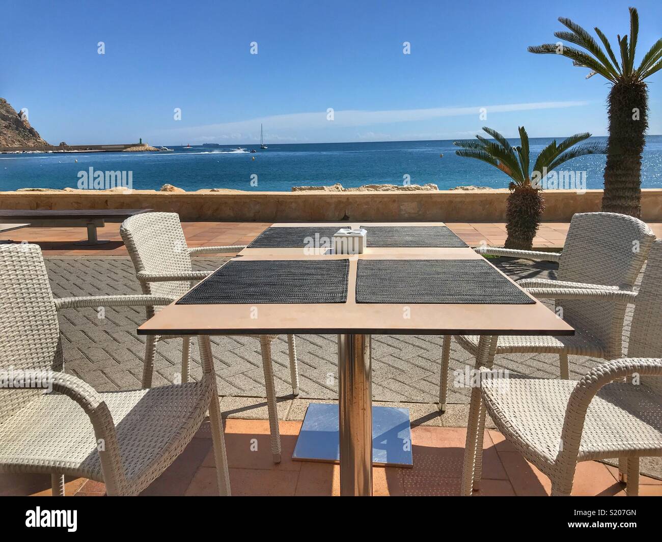 Restaurant / cafe table on the waterfront promenade in the port area of Javea / Xabia on the Costa Blanca, Alicante Province, Comunidad Valenciana, Spain - Smartphone Captured Stock Image