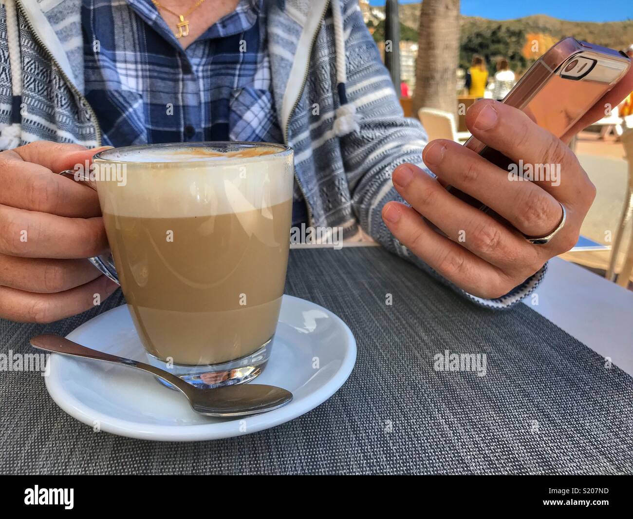 Woman checking mobile phone, having a cafe con leche, milky white coffee, in the port area of Javea / Xabia on the Costa Blanca, Alicante Province, Comunidad Valenciana, Spain - Smartphone Captured Stock Image Woman checking mobile phone, having a cafe con leche, milky white coffee, in the port area of Javea / Xabia on the Costa Blanca, Alicante Province, Comunidad Valenciana, Spain - Smartphone Captured Stock Image