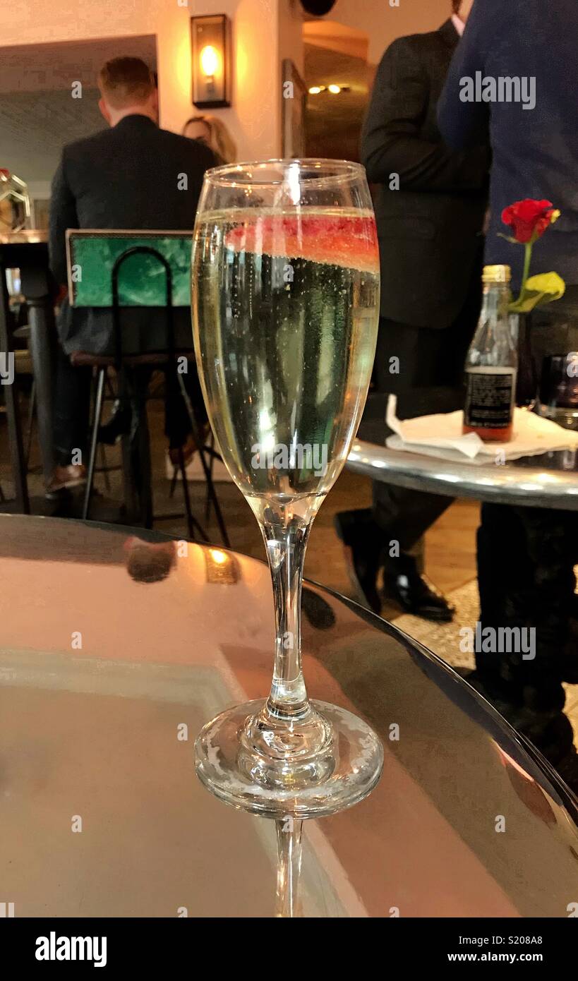 Glass of sparkling wine with a floating strawberry piece - Smartphone Captured Stock Image