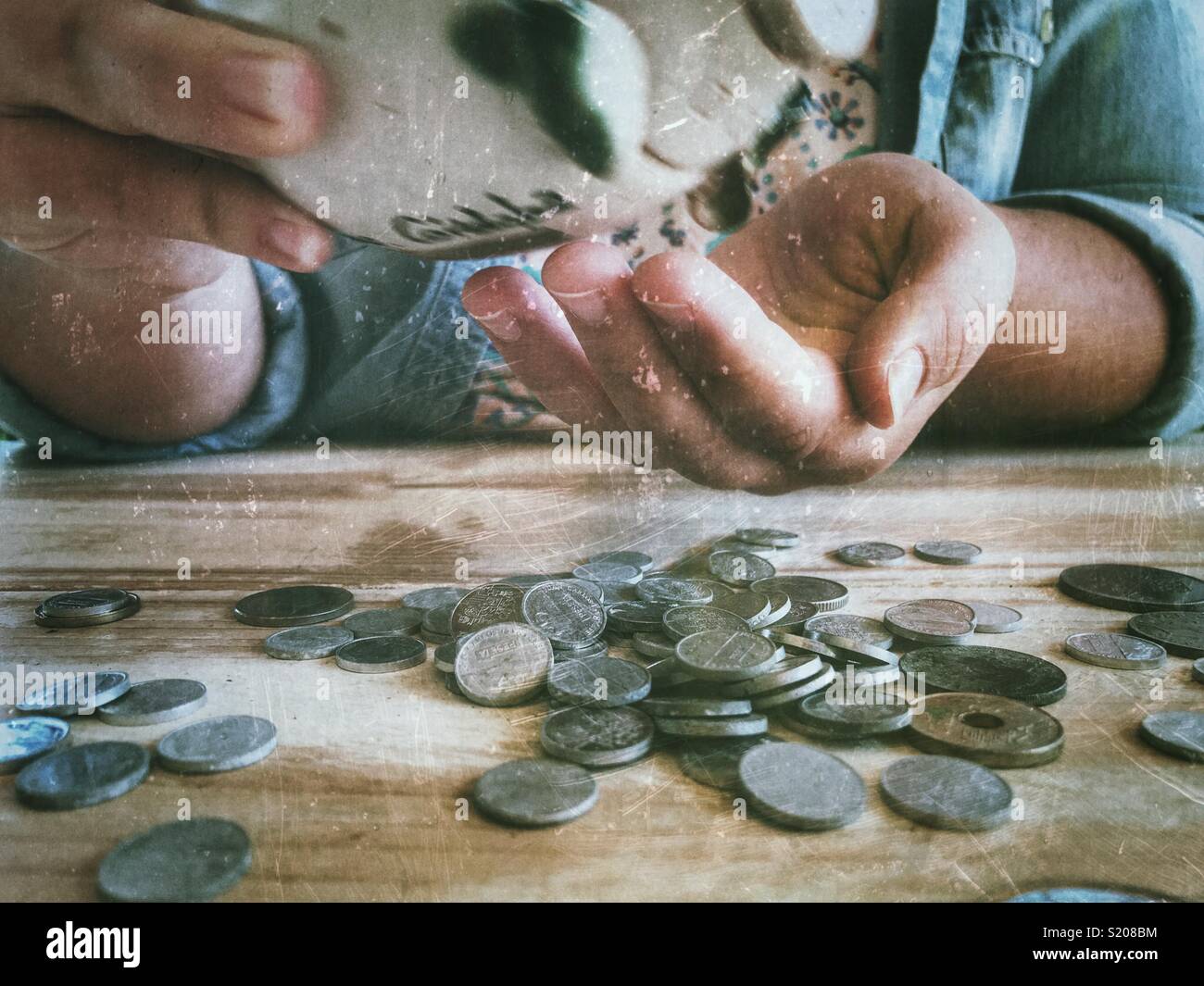 Millennial woman sitting at a table with  pile of coins and a piggy bank, midsection view - Smartphone Captured Stock Image
