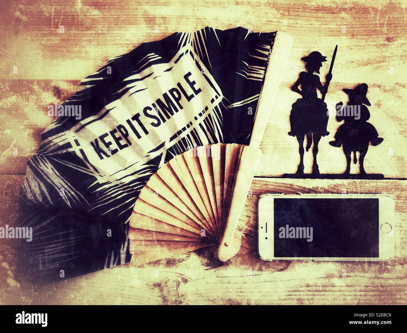 Flat-lay photography. Spanish travel theme. Keep it Simple, fan, mobile phone, Sancho Panza and Don Quixote, on a rustic wooden tabletop - Smartphone Captured Stock Image