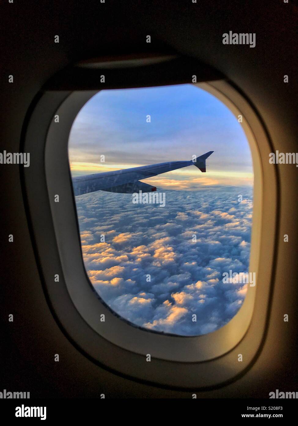 Sunset view out of the passenger window of a British Airway Airbus somewhere over Europe. Clouds and the aircraft wing complete the view. Photo Credit - © COLIN HOSKINS. - Smartphone Captured Stock Image