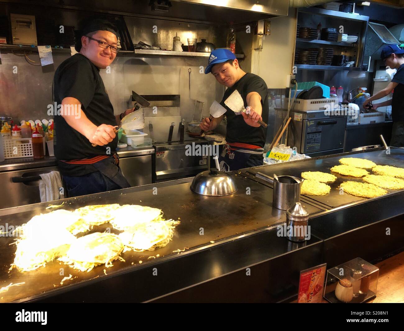 Two male cooks preparing food in a Japanese restaurant in Hiroshima. - Smartphone Captured Stock Image