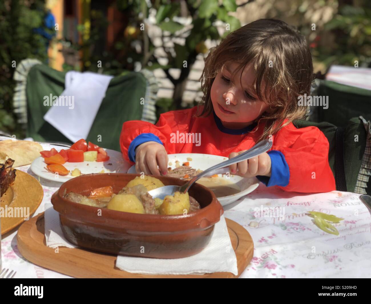 Little girl eating at restaurant Stock Photo