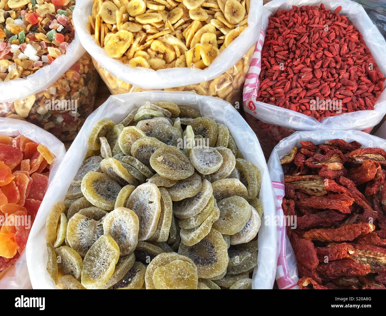 Dried fruits stall, including goji berries, sun dried tomatoes, kiwi fruit, bananas, and papaya, at an outdoor market in Javea, Spain. Stock Photo