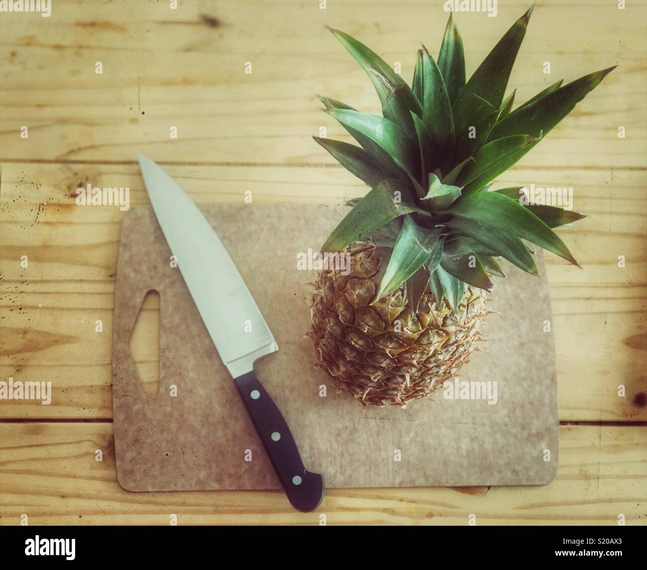 Whole pineapple and large knife on cutting board Stock Photo
