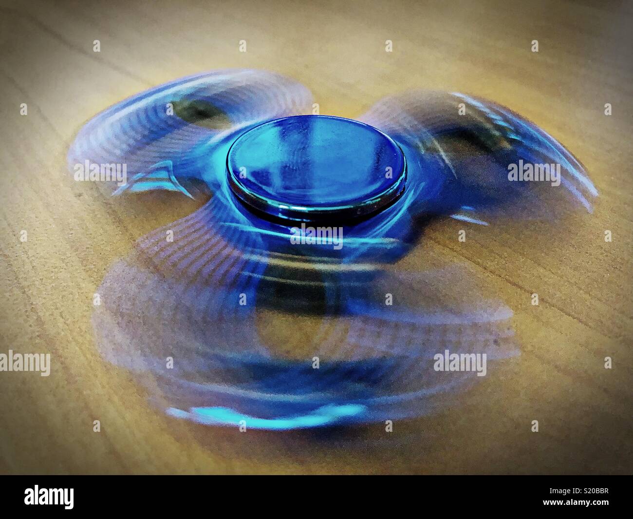 A spinning fidget spinner on a desktop Stock Photo