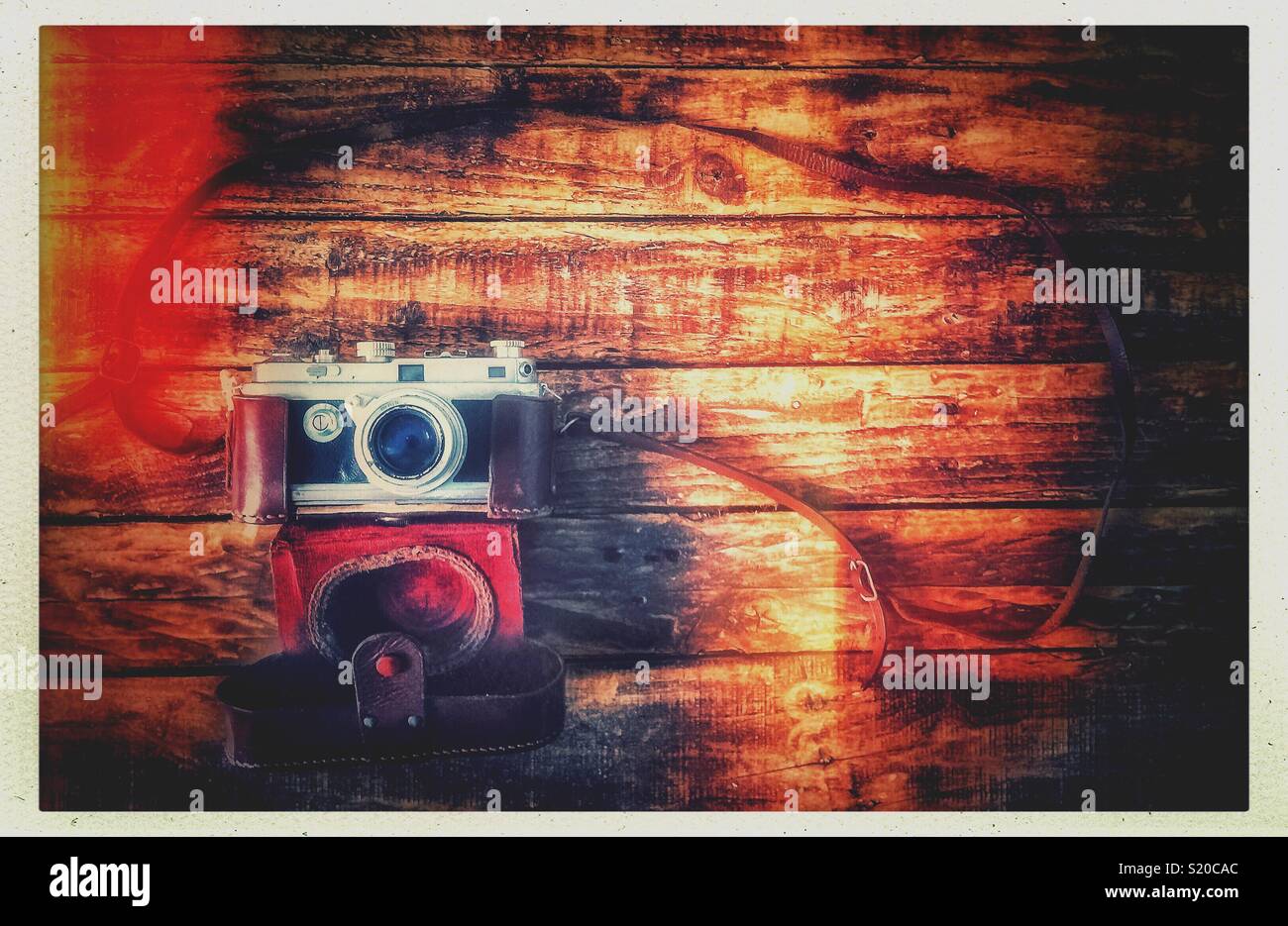Flat lay picture of a vintage camera with its leather case on a grungy wooden table. - Smartphone Captured Stock Image