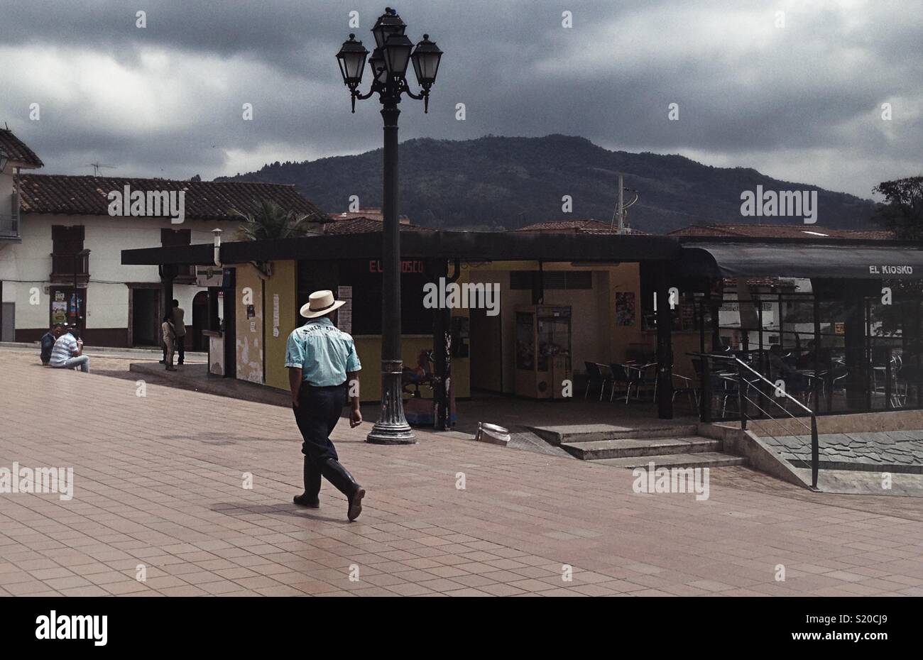 A local Colombian man walking across a Square in Antioquia - Smartphone Captured Stock Image