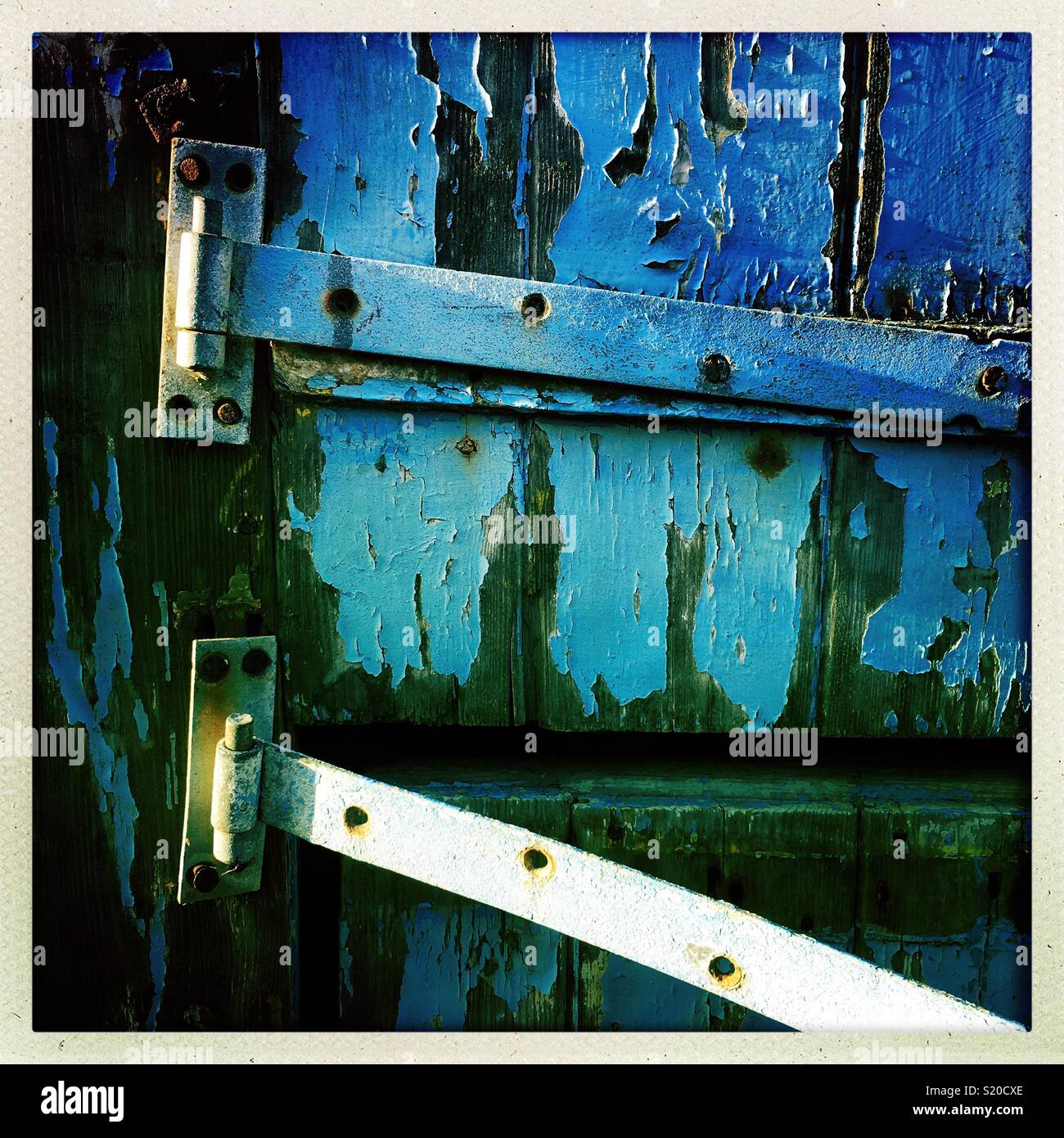 Urban decay; peeling blue paint and hinges. Stock Photo