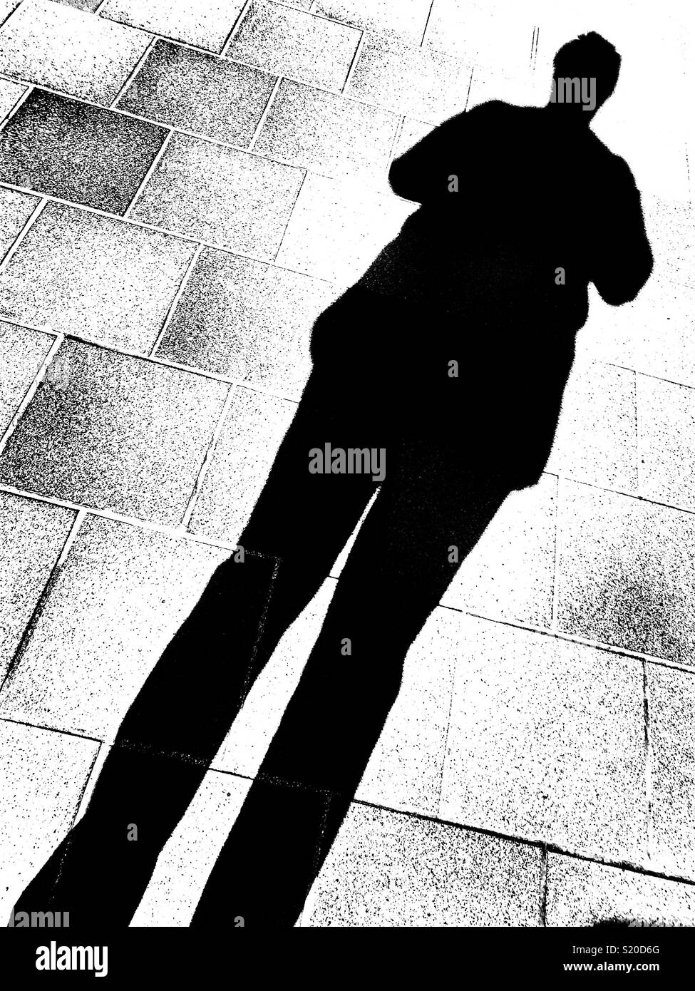 Human shadow on a tiled floor, monochrome Stock Photo