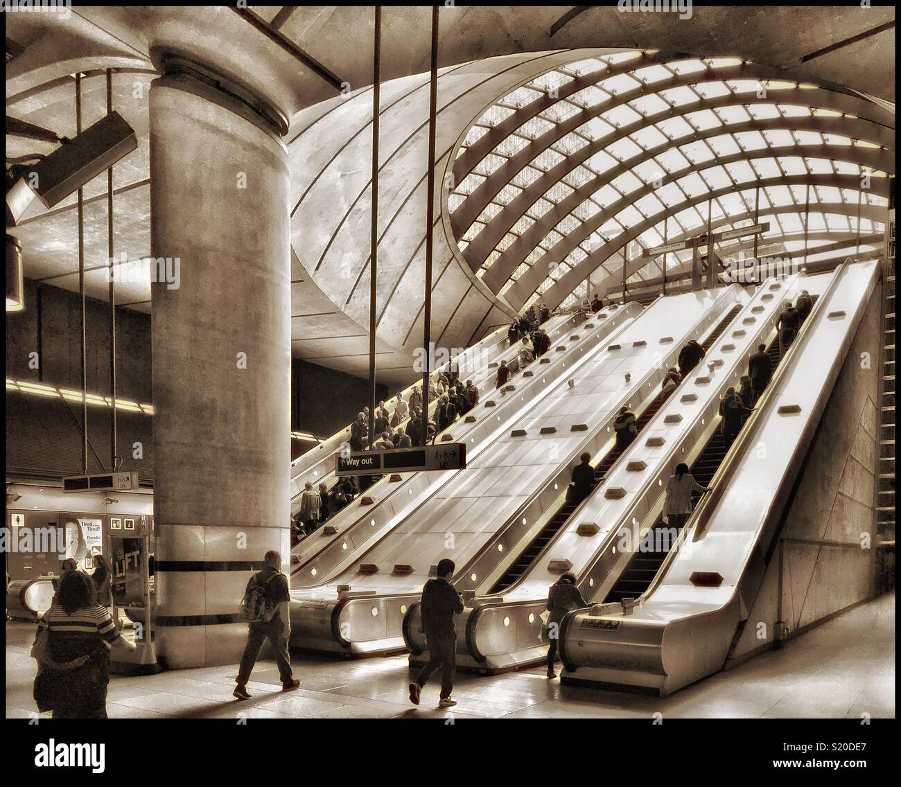 The escalators & commuters at Canary Wharf Underground Station in London, England. This Tube Station is on the Jubilee Line and is part of the Docklands Light Railway. Photo Credit - © COLIN HOSKINS. - Smartphone Captured Stock Image