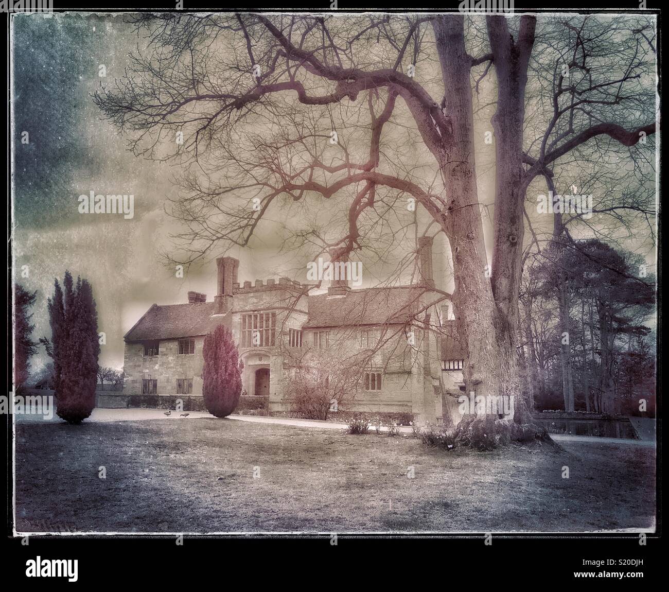 An atmospheric, retro, grunge effect image of the Grade 1 Listed Moated Manor House at Baddesley Clinton, Warwickshire, England. This house has been used as a film location. Photo - © COLIN HOSKINS. - Smartphone Captured Stock Image