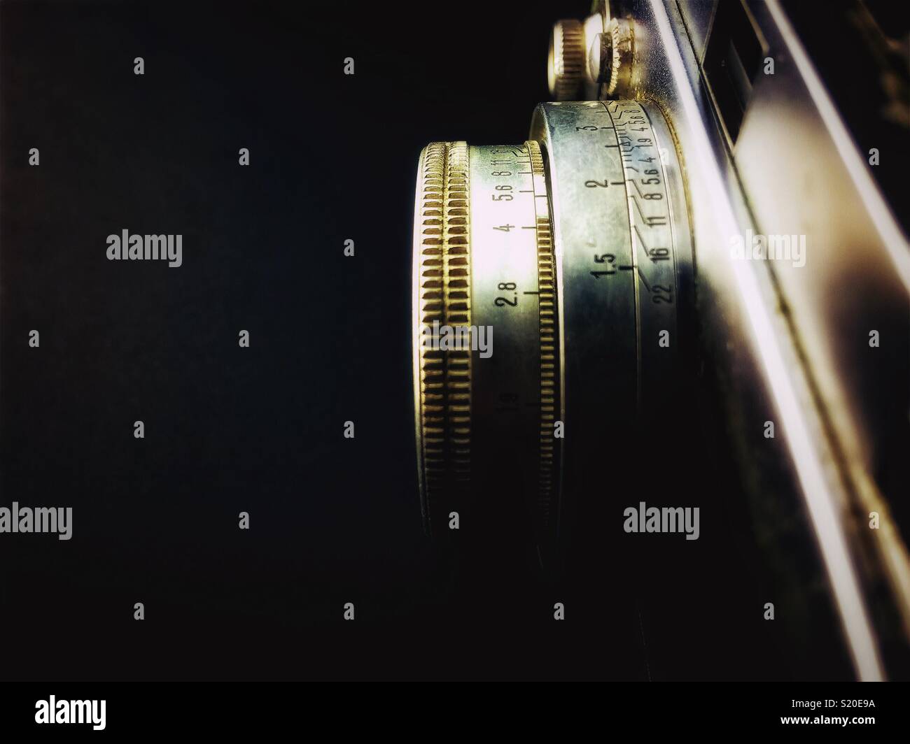 Closeup on a vintage lens with the values of focal length and aperture, isolated on a black background with copy space. - Smartphone Captured Stock Image