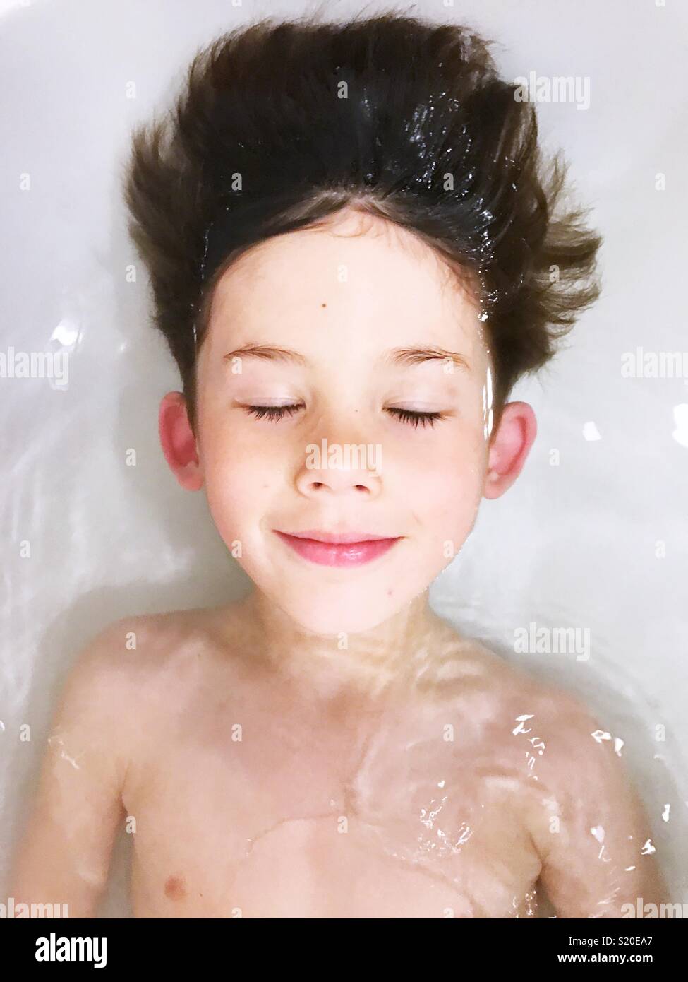 The happy face of a boy taking a relaxing bath Stock Photo