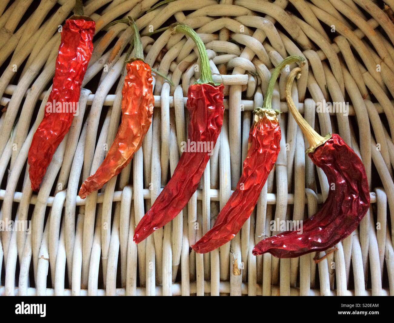 Five dried red chillies on a wicker tray - Smartphone Captured Stock Image