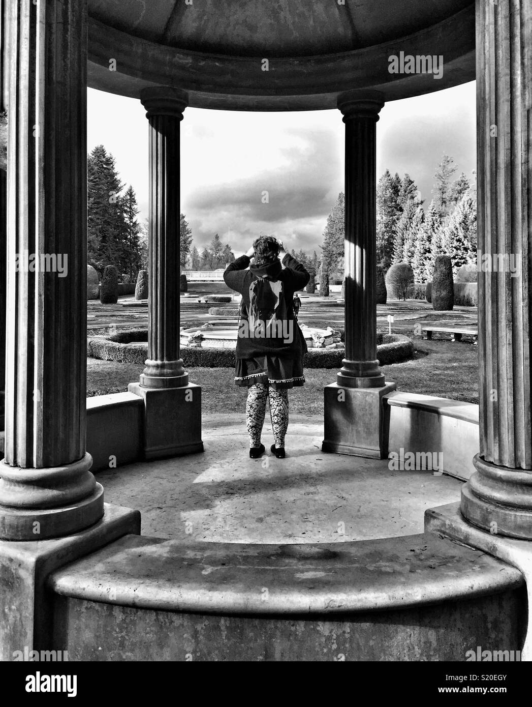 Young woman photographs from Centennial Gazebo in Duncan garden built in 2004, Manito park, Spokane, WA - Smartphone Captured Stock Image