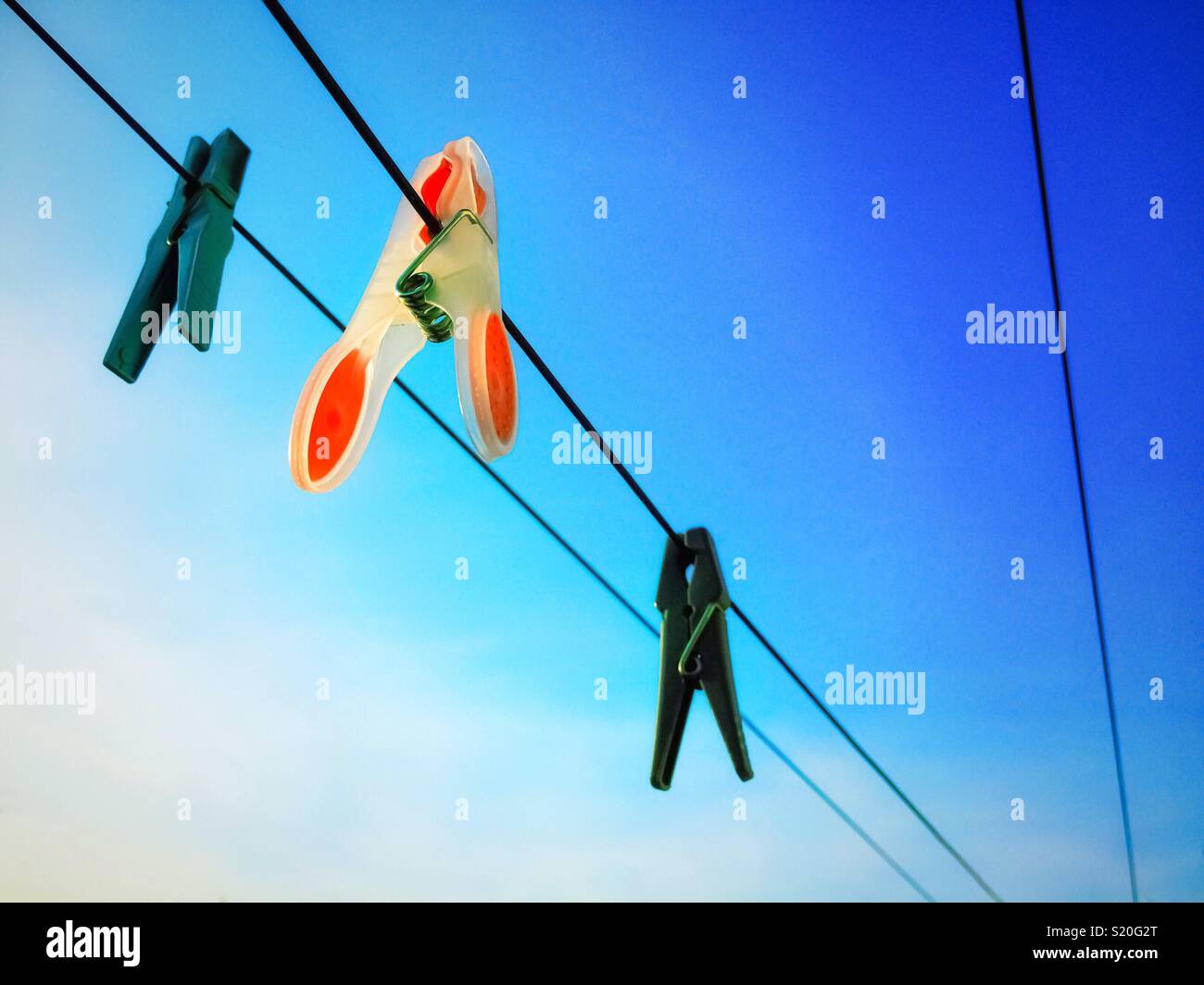 Washing lines with hanging clothing pegs on a blue sky background. - Smartphone Captured Stock Image