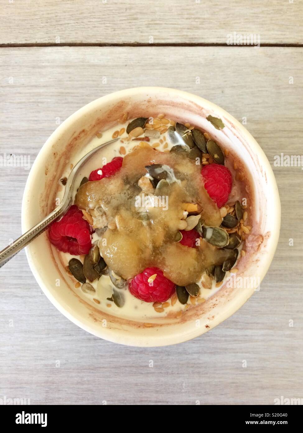 Chocolate porridge oats with yoghurt, raspberries, pumpkin seeds, cream & honey in a bowl - Smartphone Captured Stock Image
