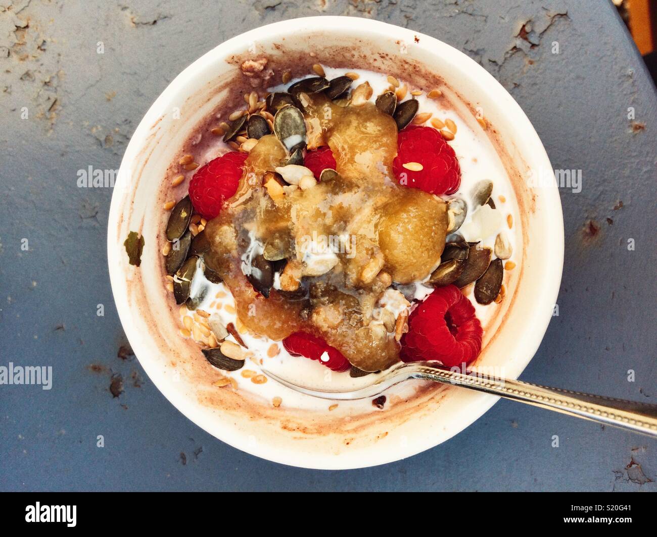 Bowl of chocolate porridge oats with yoghurt, raspberries, pumpkin seeds, cream & honey - Smartphone Captured Stock Image