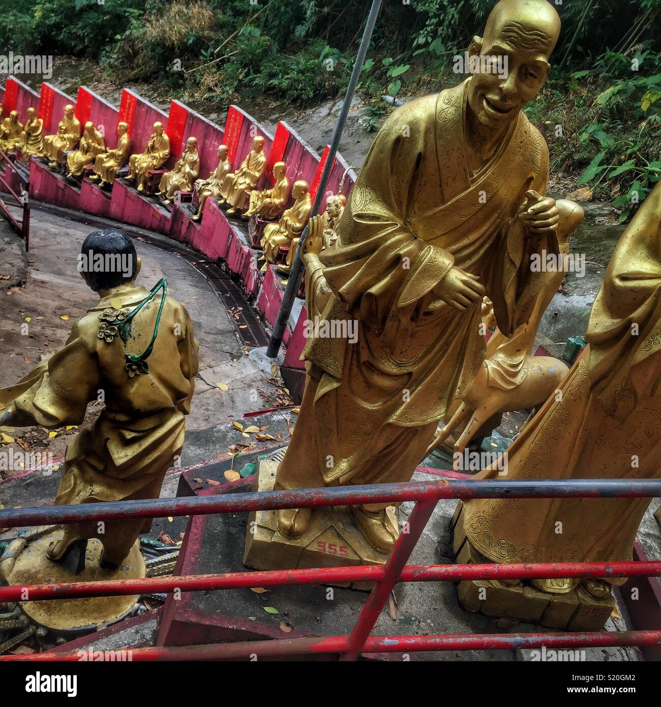Golden statues of Buddhist 'arhats' line the path leading to the Ten Thousand Buddhas Monastery in Sha Tin, New Territories, Hong Kong - Smartphone Captured Stock Image