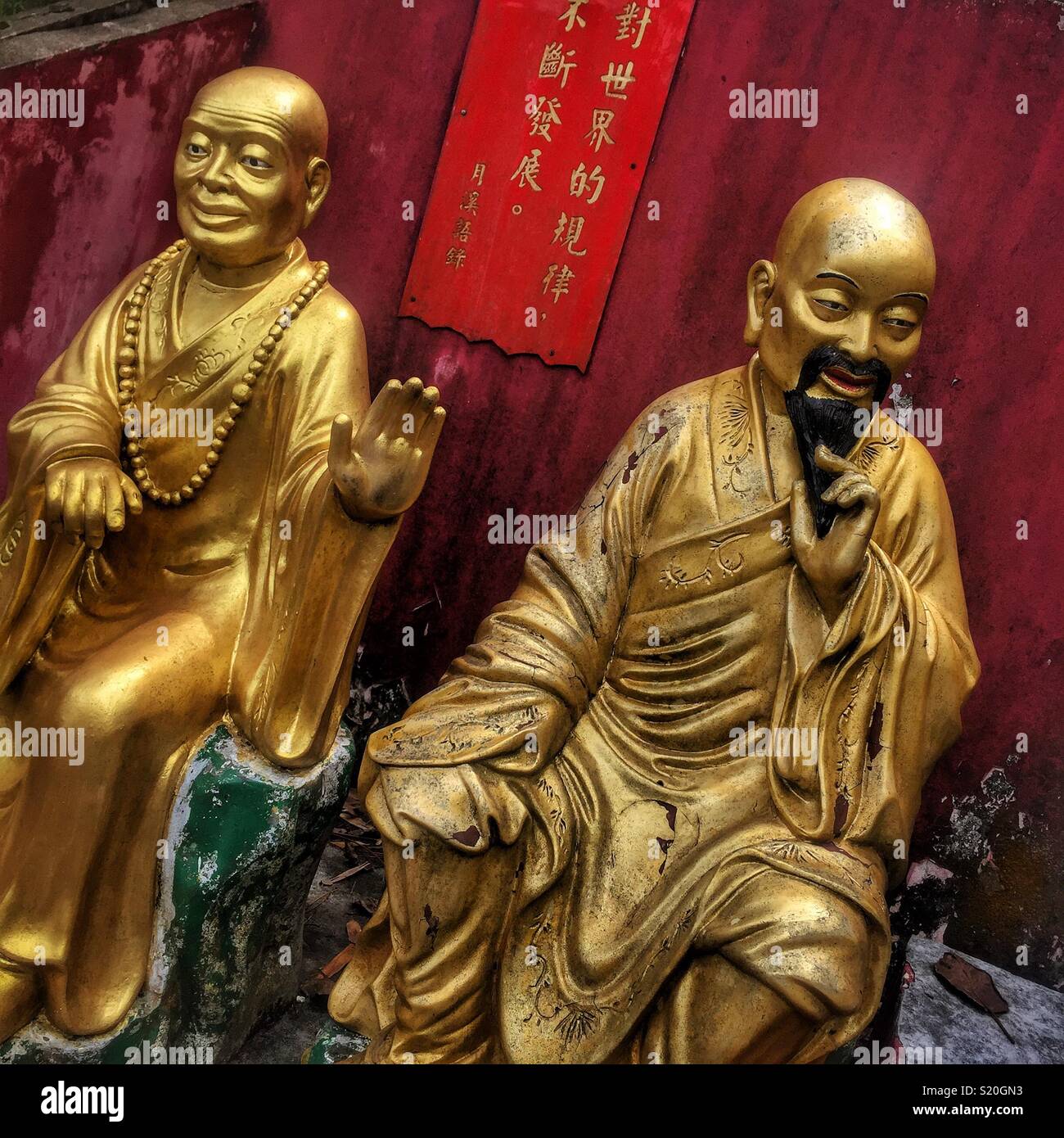 Some of the Golden statues of Buddhist 'arhats' lining the path leading to the Ten Thousand Buddhas Monastery in Sha Tin, New Territories, Hong Kong - Smartphone Captured Stock Image