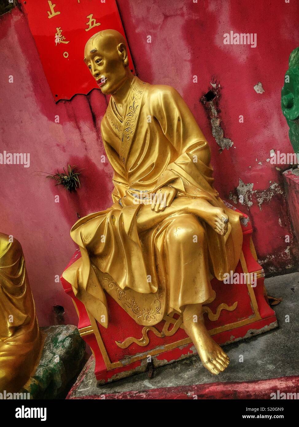 One of the Golden statues of Buddhist 'arhats' lining the path leading to the Ten Thousand Buddhas Monastery in Sha Tin, New Territories, Hong Kong - Smartphone Captured Stock Image