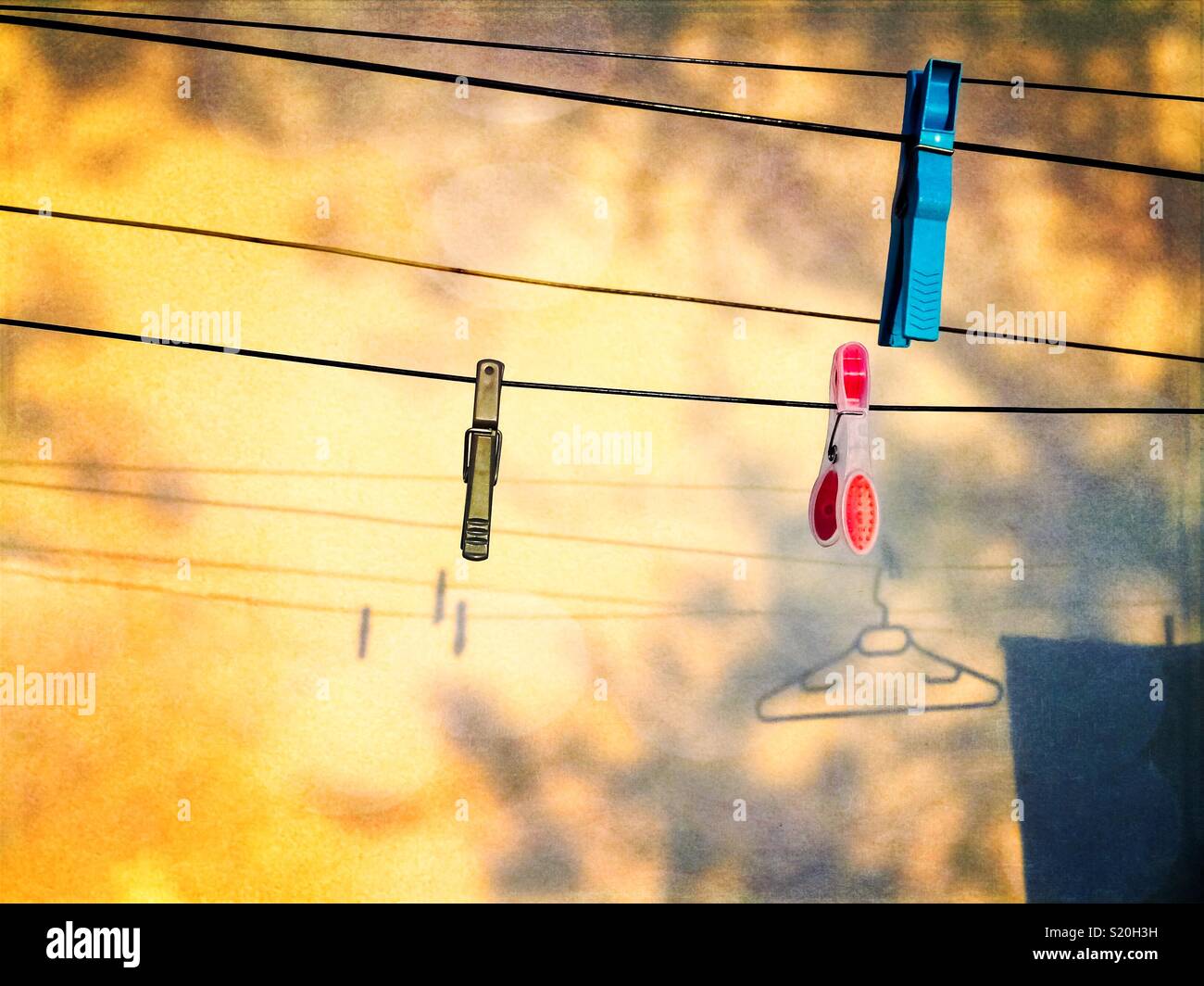 Clothing pins hung to washing lines with projected shadows on a wall at golden hour with copy space. - Smartphone Captured Stock Image
