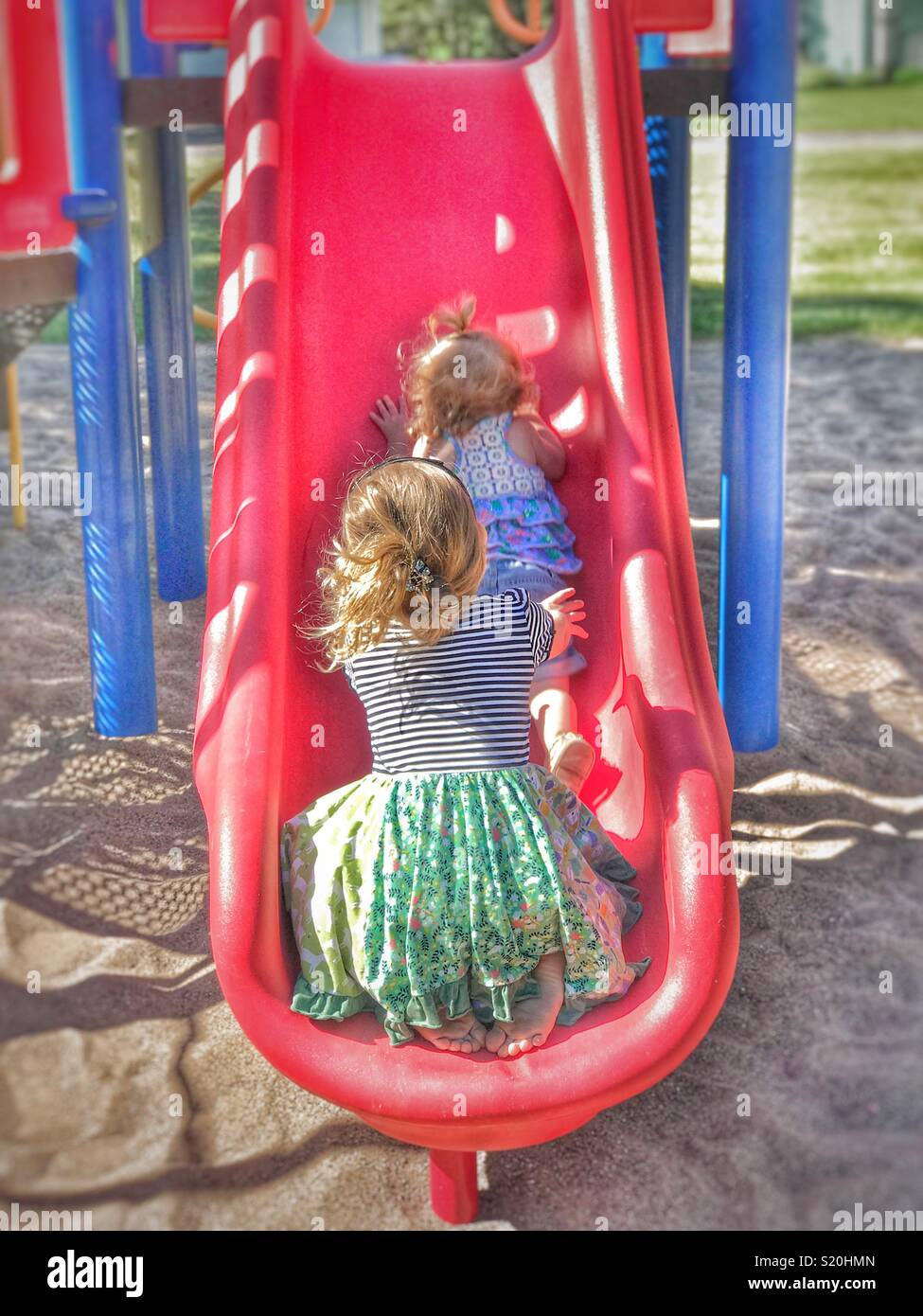 Girl catching her little sister coming down the slide Stock Photo