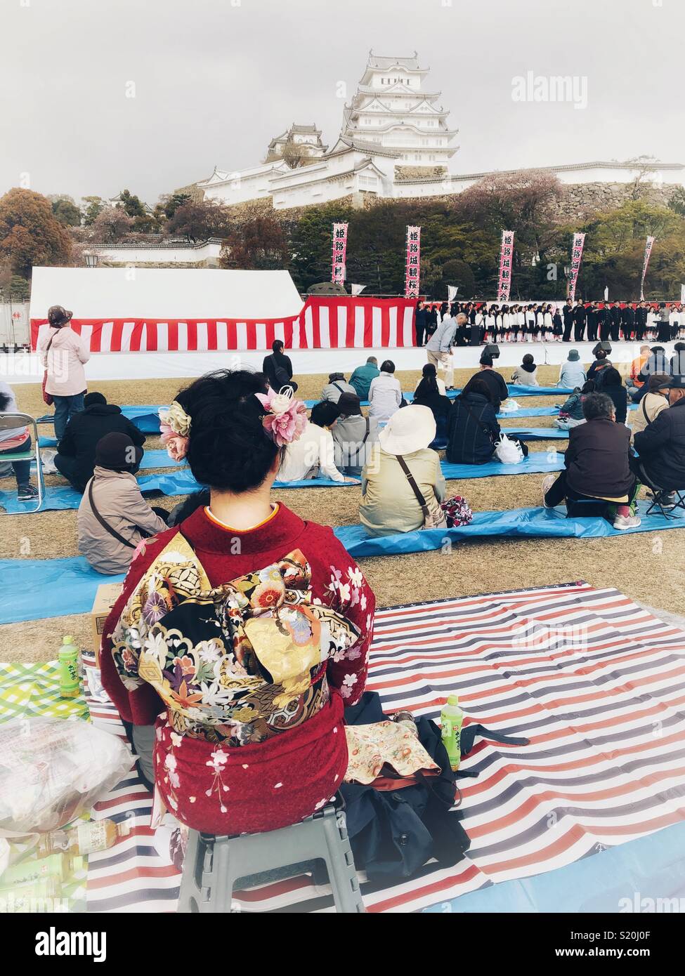 Woman dressed in a red kimono enjoys the Cherry Blossom Festival in Himeji, Japan. - Smartphone Captured Stock Image