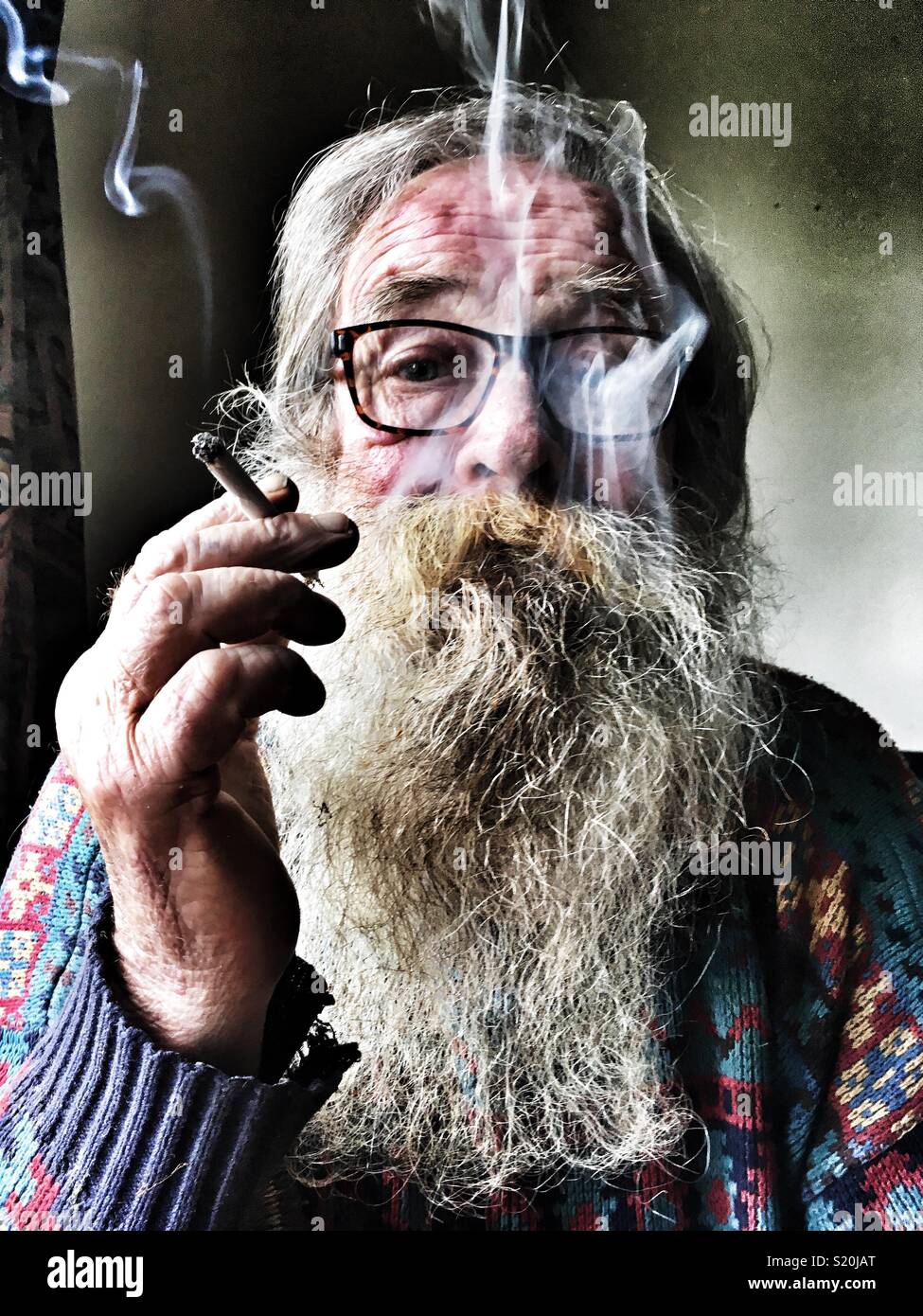 Elderly man smoking a hand rolled cigarette Stock Photo