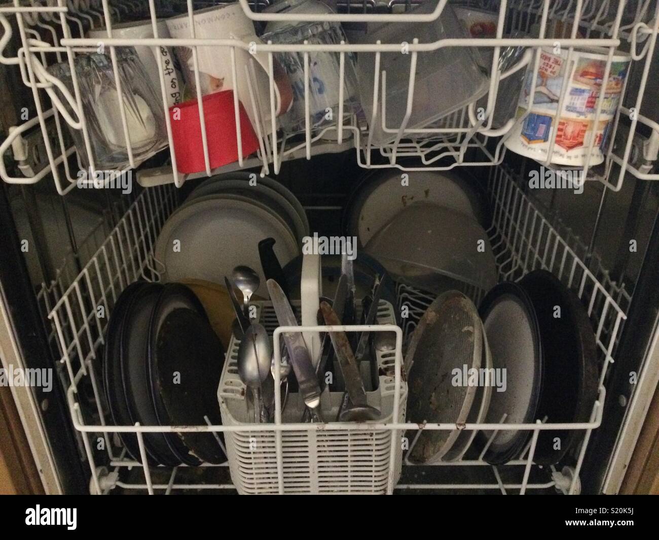 Ready to go dishwasher full of dirty crockery and cutlery Stock Photo