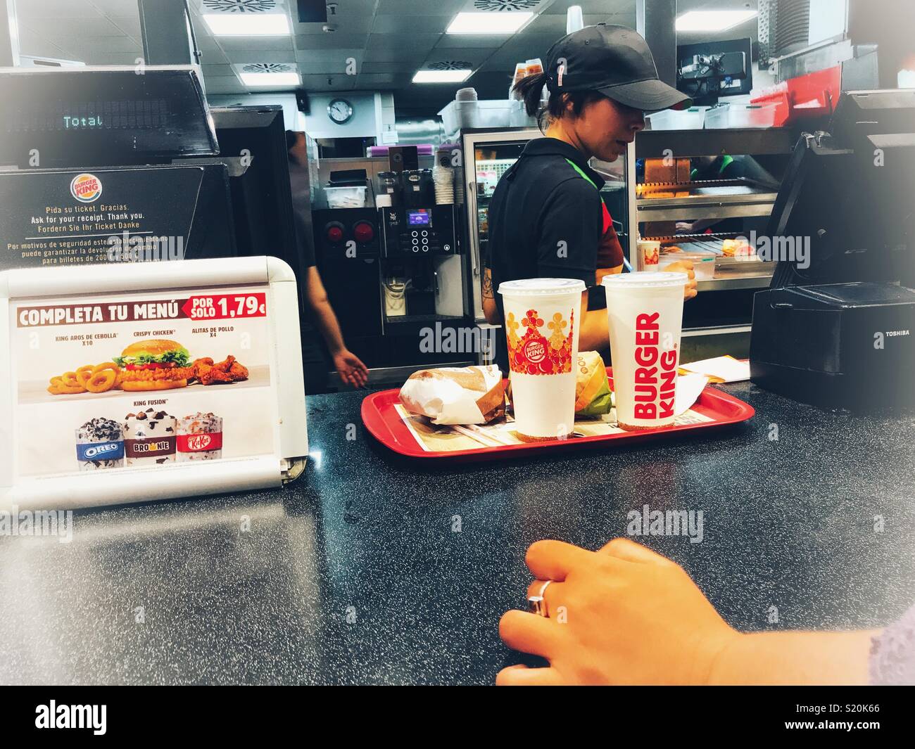 Woman waiting for her order to be completed at the Burger King food outlet, El Altet Airport, Alicante, Spain Stock Photo