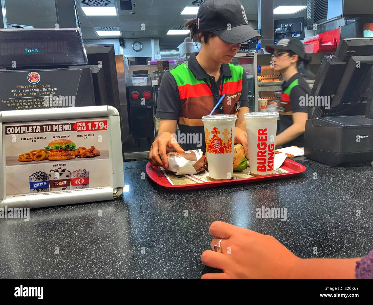 Woman waiting for her food order to be completed at the Burger King fast-food outlet, El Altet Airport, Alicante, Spain Stock Photo