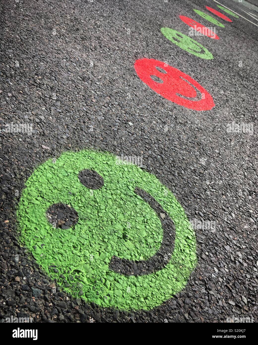 Green and red smiley faces on the road, leftovers from Southampton Half Marathon pitting on a brave face Stock Photo