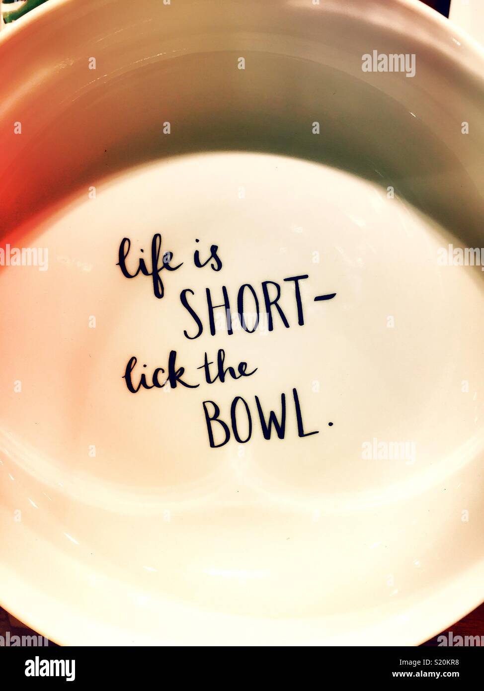 White serving bowl with humorous inscription life is short lick the bowl, USA - Smartphone Captured Stock Image