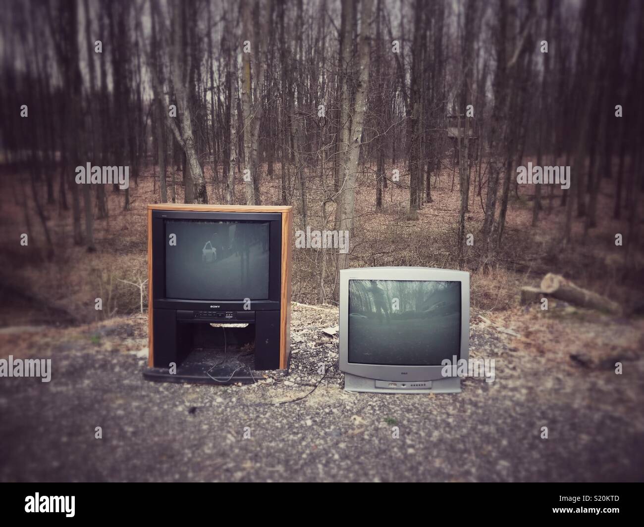 Two old school tube televisions sitting outside in the woods. Stock Photo